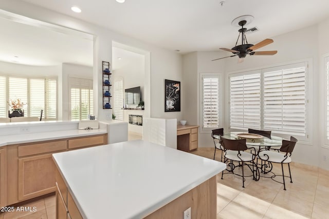 kitchen featuring ceiling fan, light brown cabinetry, a center island, and light tile patterned floors