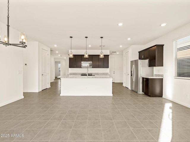 kitchen with pendant lighting, appliances with stainless steel finishes, light tile patterned flooring, a center island with sink, and dark brown cabinets