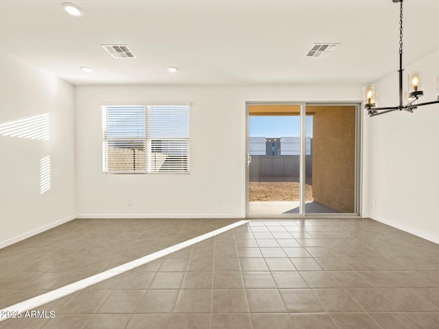 empty room with tile patterned flooring, plenty of natural light, and a notable chandelier