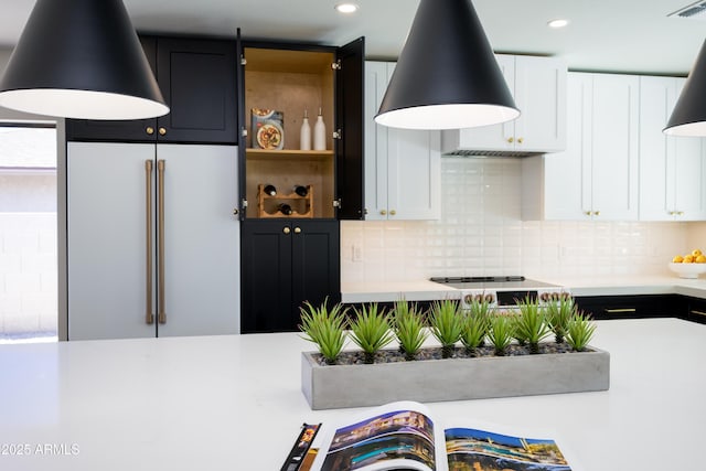 kitchen with high end fridge, white cabinetry, ventilation hood, black electric cooktop, and decorative backsplash