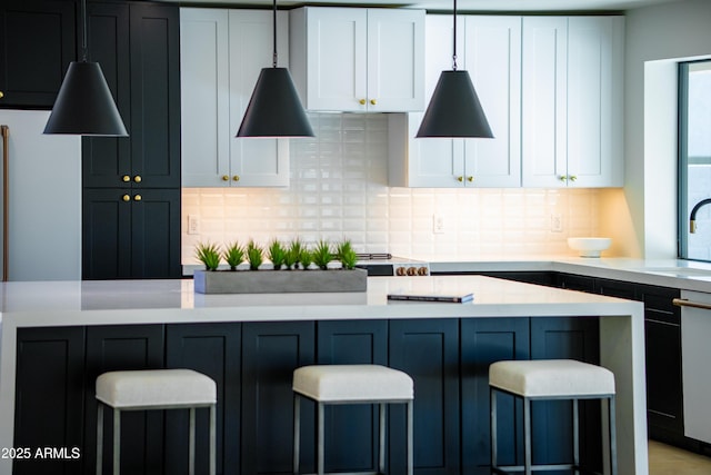 kitchen with sink, decorative backsplash, a breakfast bar, and white cabinets