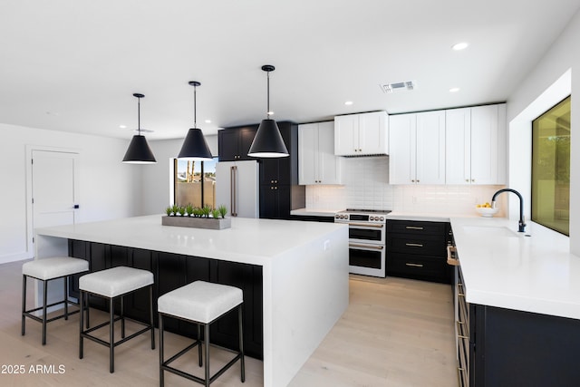 kitchen with a kitchen bar, sink, high end appliances, decorative light fixtures, and a kitchen island