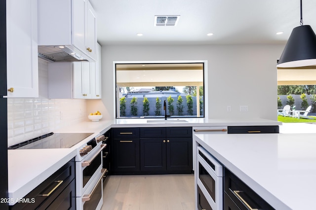 kitchen with white cabinetry, hanging light fixtures, stainless steel microwave, and range with two ovens