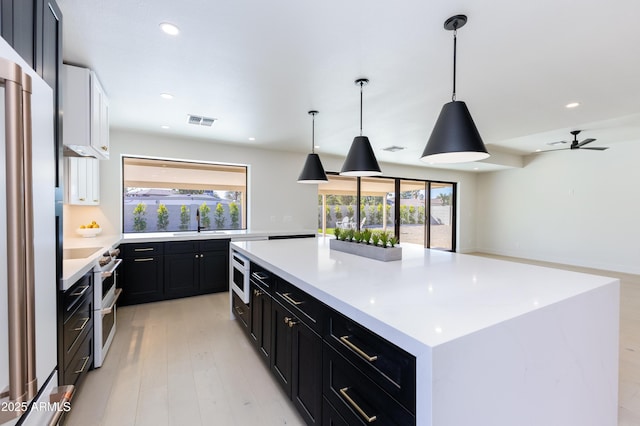 kitchen featuring a healthy amount of sunlight, pendant lighting, white appliances, and a spacious island