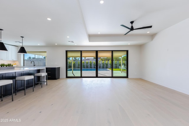 living room featuring ceiling fan, sink, and light hardwood / wood-style floors