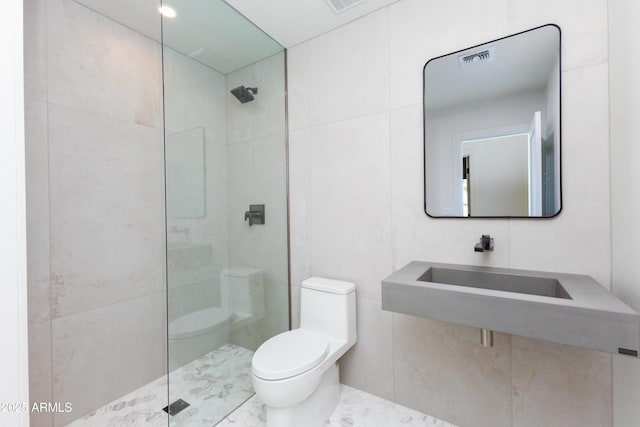 bathroom with toilet, sink, tile walls, and a tile shower