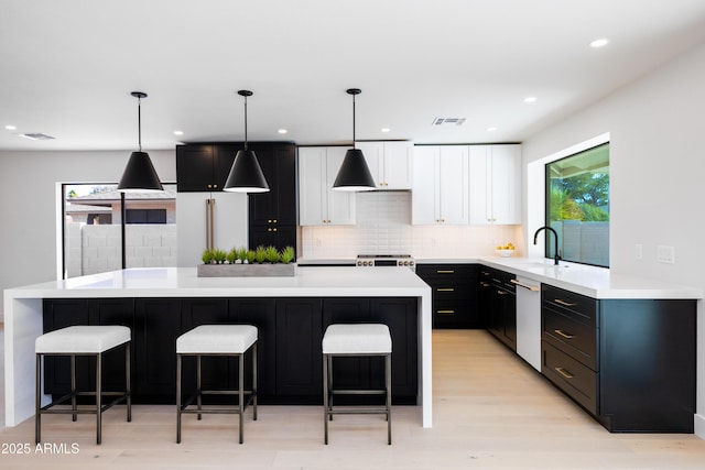 kitchen featuring white cabinetry, hanging light fixtures, stainless steel dishwasher, and a kitchen island