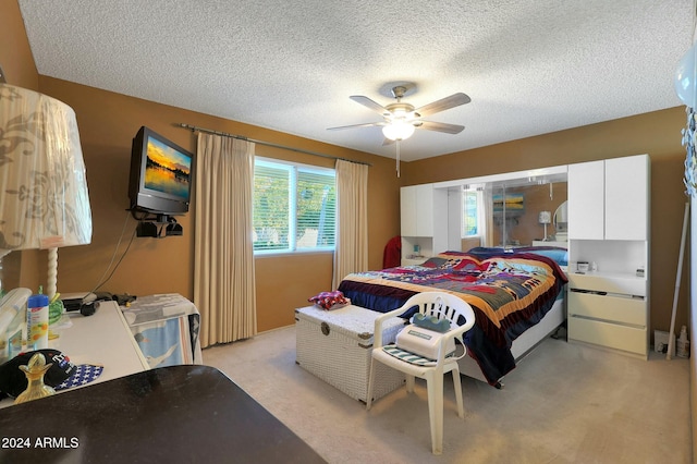 carpeted bedroom featuring ceiling fan and a textured ceiling