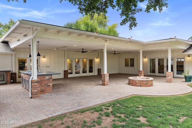 3817 E Highland Ave, Phoenix, AZ 85018 - back of property featuring board and batten siding, exterior kitchen, an outdoor fire pit, a patio area, and a ceiling fan