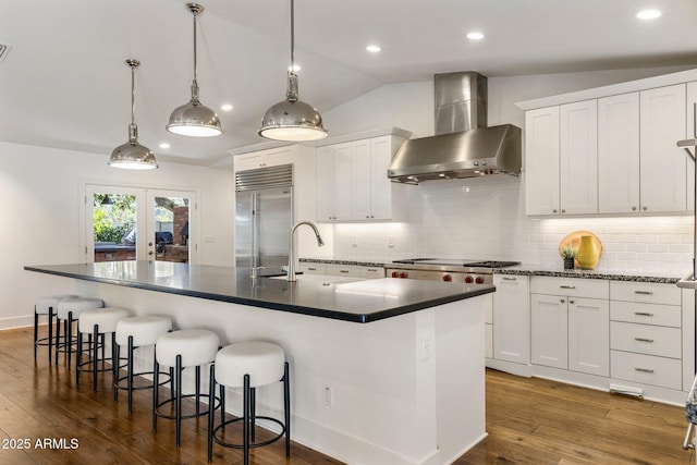 3817 E Highland Ave, Phoenix, AZ 85018 - kitchen with wall chimney range hood, stainless steel appliances, a sink, dark countertops, and dark wood finished floors