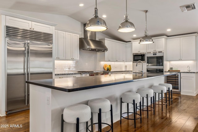 3817 E Highland Ave, Phoenix, AZ 85018 - kitchen featuring built in appliances, beverage cooler, vaulted ceiling, dark wood-type flooring, and wall chimney exhaust hood