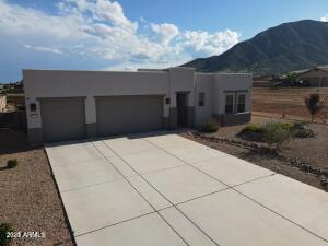 southwest-style home with an attached garage, a mountain view, concrete driveway, and stucco siding