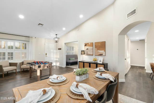 dining space with a chandelier, high vaulted ceiling, and dark wood-type flooring