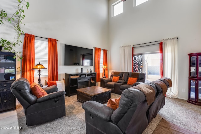 living room with a wealth of natural light, a high ceiling, and light colored carpet