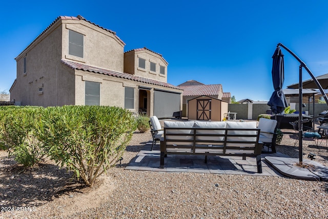 back of house featuring a patio area, an outdoor living space, and a storage unit