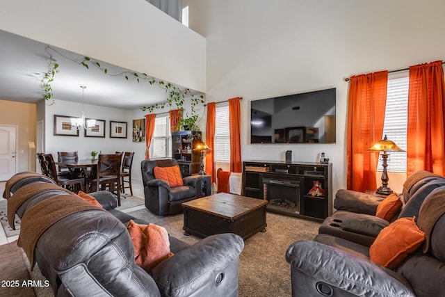 carpeted living room with a towering ceiling, plenty of natural light, and a chandelier