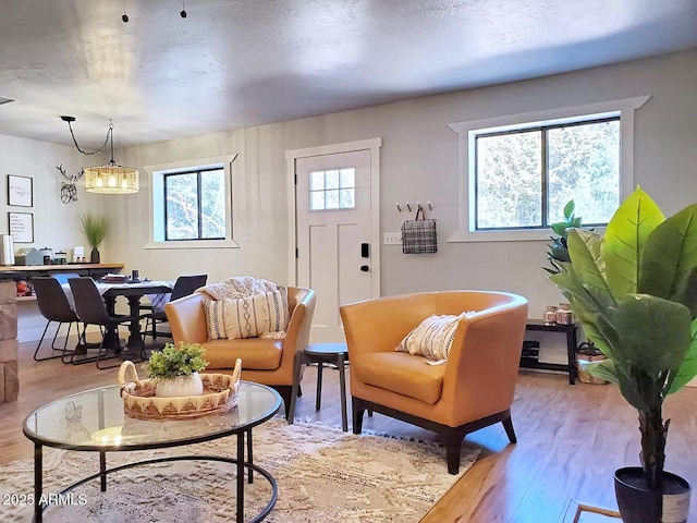 living room featuring a textured ceiling, light hardwood / wood-style flooring, and a chandelier