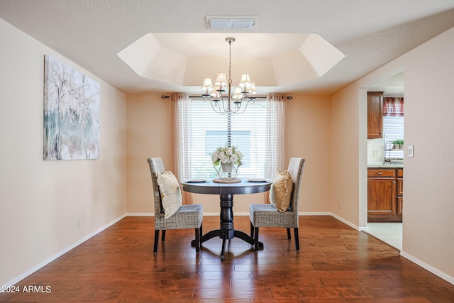 dining area featuring dark hardwood / wood-style flooring, a raised ceiling, and a notable chandelier