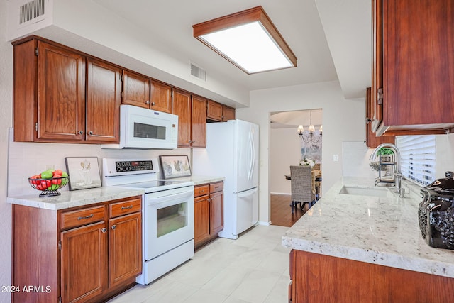 kitchen with sink, tasteful backsplash, light stone counters, a notable chandelier, and white appliances