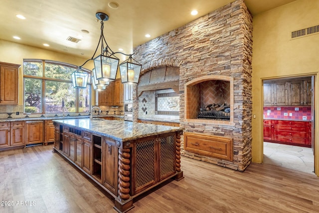 9980 E Charter Oak Rd, Scottsdale, AZ 85260 - kitchen with decorative light fixtures, tasteful backsplash, dark stone counters, a center island, and light wood-type flooring
