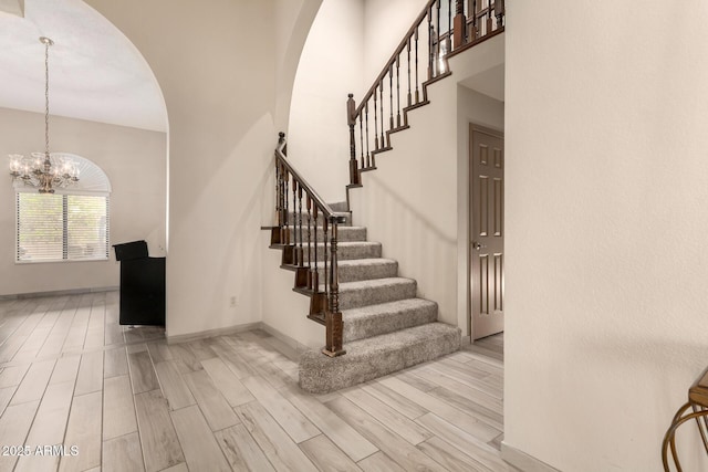 staircase with a chandelier, arched walkways, and baseboards