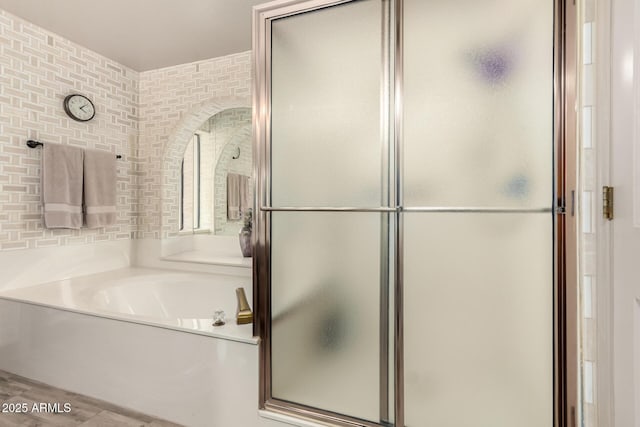 bathroom featuring a shower stall, a garden tub, and wood finished floors