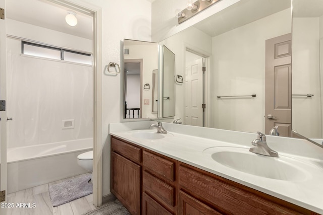 bathroom with a sink, toilet, double vanity, and shower / bathing tub combination