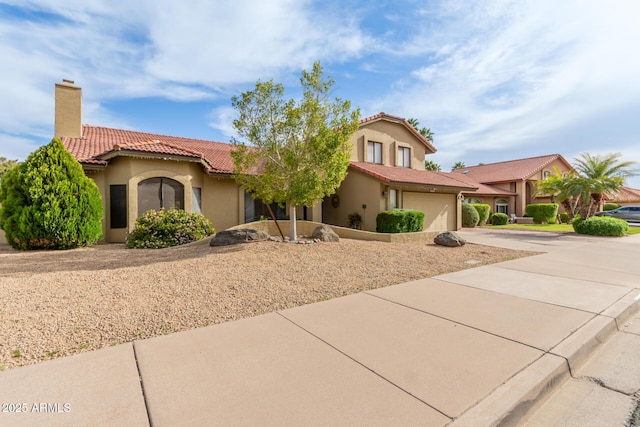 mediterranean / spanish house with driveway, stucco siding, a tiled roof, and a chimney