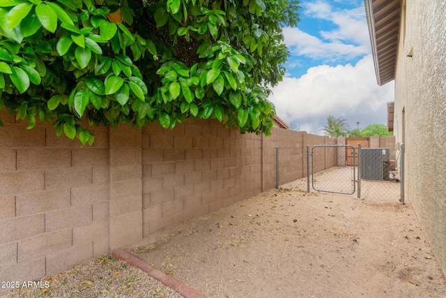 view of yard featuring central AC, a fenced backyard, and a gate