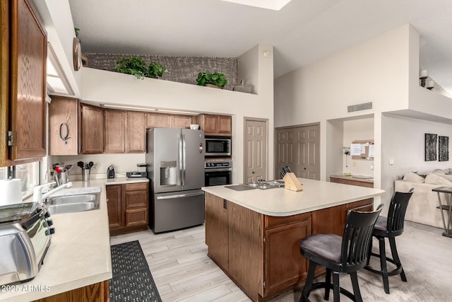 kitchen with a kitchen island, visible vents, appliances with stainless steel finishes, high vaulted ceiling, and a sink