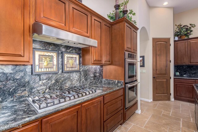 kitchen with decorative backsplash, dark stone countertops, and stainless steel appliances