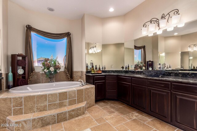 bathroom featuring tiled tub and vanity