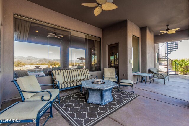 view of patio featuring a mountain view, ceiling fan, and an outdoor living space with a fire pit