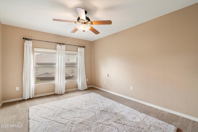 carpeted empty room featuring a ceiling fan and baseboards