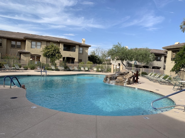 community pool with a patio area and fence