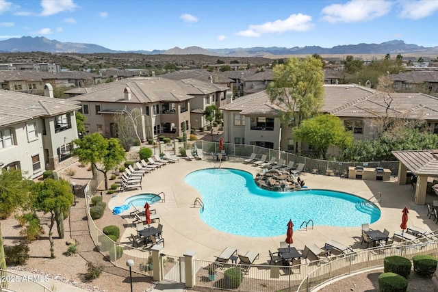 community pool with a mountain view, a residential view, a patio, and fence