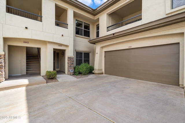 view of front of house featuring stucco siding, stone siding, a garage, and driveway