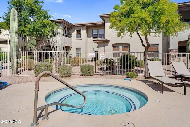 view of swimming pool featuring a hot tub and fence