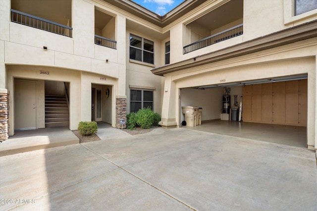 exterior space featuring concrete driveway, an attached garage, stone siding, and stucco siding