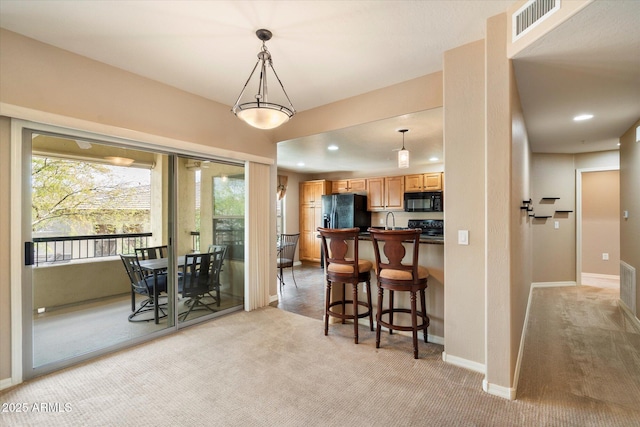 kitchen with visible vents, a kitchen bar, light carpet, recessed lighting, and black appliances