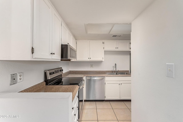 kitchen with light tile patterned floors, stainless steel appliances, a sink, visible vents, and white cabinets