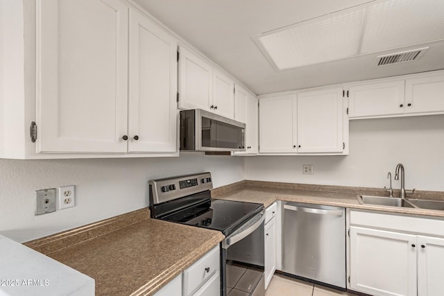 kitchen featuring visible vents, white cabinets, stainless steel appliances, a sink, and light tile patterned flooring