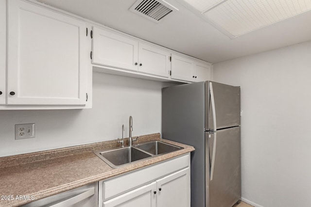 kitchen featuring appliances with stainless steel finishes, a sink, visible vents, and white cabinets