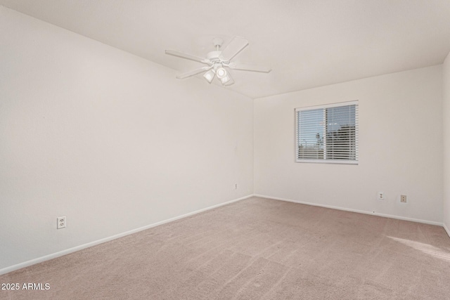 spare room featuring light carpet, a ceiling fan, and baseboards