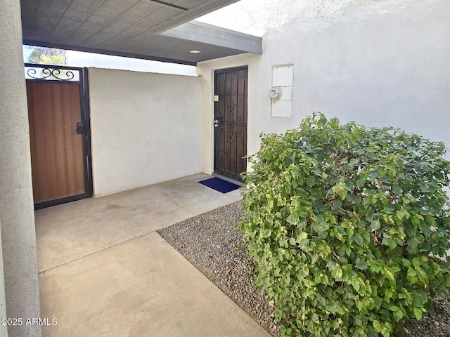 view of exterior entry with a gate and stucco siding