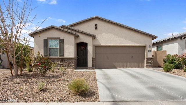 mediterranean / spanish home with stone siding, stucco siding, an attached garage, and driveway