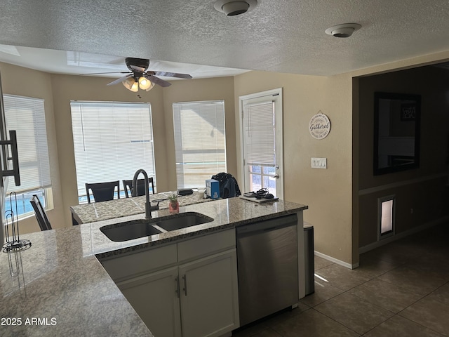 kitchen featuring white cabinetry, sink, ceiling fan, dark tile patterned floors, and stainless steel dishwasher