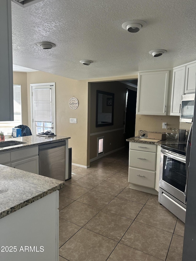 kitchen with white cabinets, sink, tile patterned floors, and appliances with stainless steel finishes