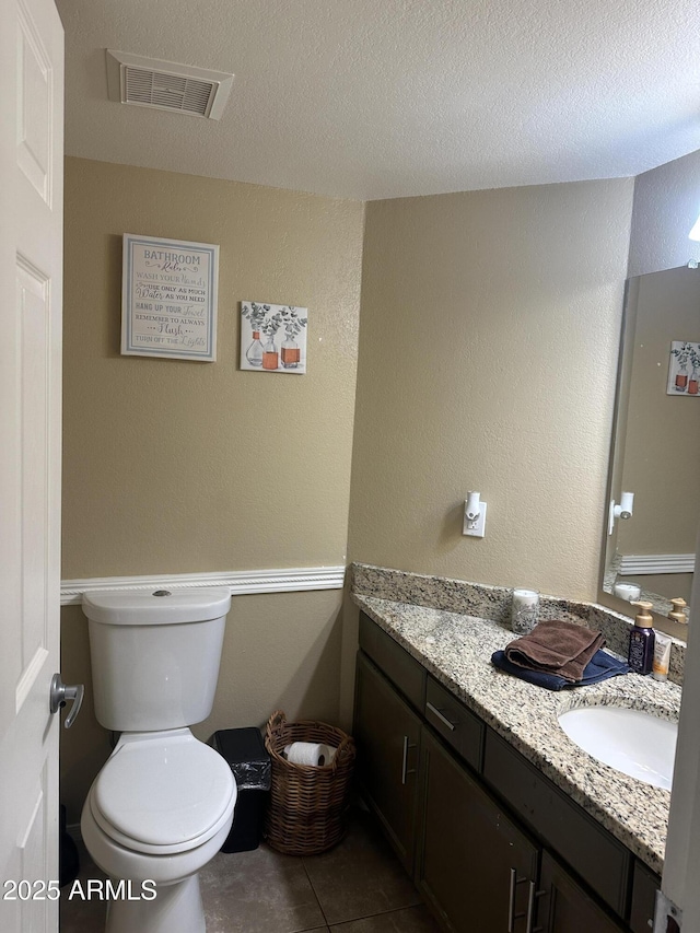 bathroom featuring tile patterned floors, vanity, toilet, and a textured ceiling