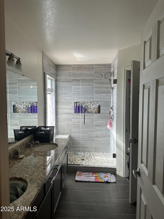 bathroom featuring vanity, a textured ceiling, tile walls, and a shower with shower door